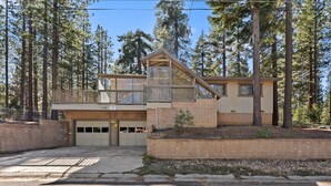 Ein zweistöckiges Haus mit Garage, umgeben von hohen Kiefern.