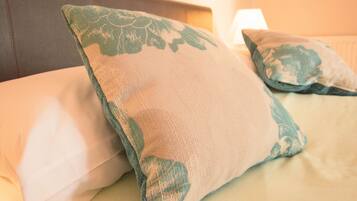 A bed with two pillows, one with a floral pattern and the other plain.