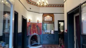 A hallway with patterned flooring, a chandelier, and a fireplace. - Pinegrove Hotel (Carlisle)