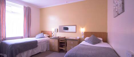 A hotel room with two beds, a desk, and a television.