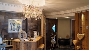 Een receptie met een houten balie, een kroonluchter, een hertenbeeld en een hartdecoratie aan de muur.