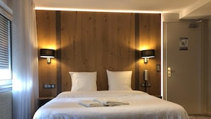 Hotelkamer met een groot bed, twee bedlampen, een wand van houten panelen en een deur met slot.