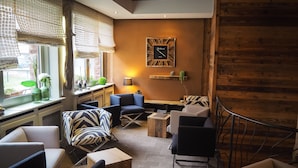 Een gezellige zithoek met een bank, fauteuils, een bijzettafeltje en een houten accentmuur.
