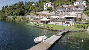 Ein Hotel am Wasser mit einer Anlegestelle, Liegestühlen und einem kleinen Boot.