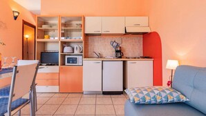 Eine kleine Küche mit Essbereich, einer Couch und einer Lampe.