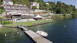Hotel aan het water met een steiger, ligbedden en een klein bootje.