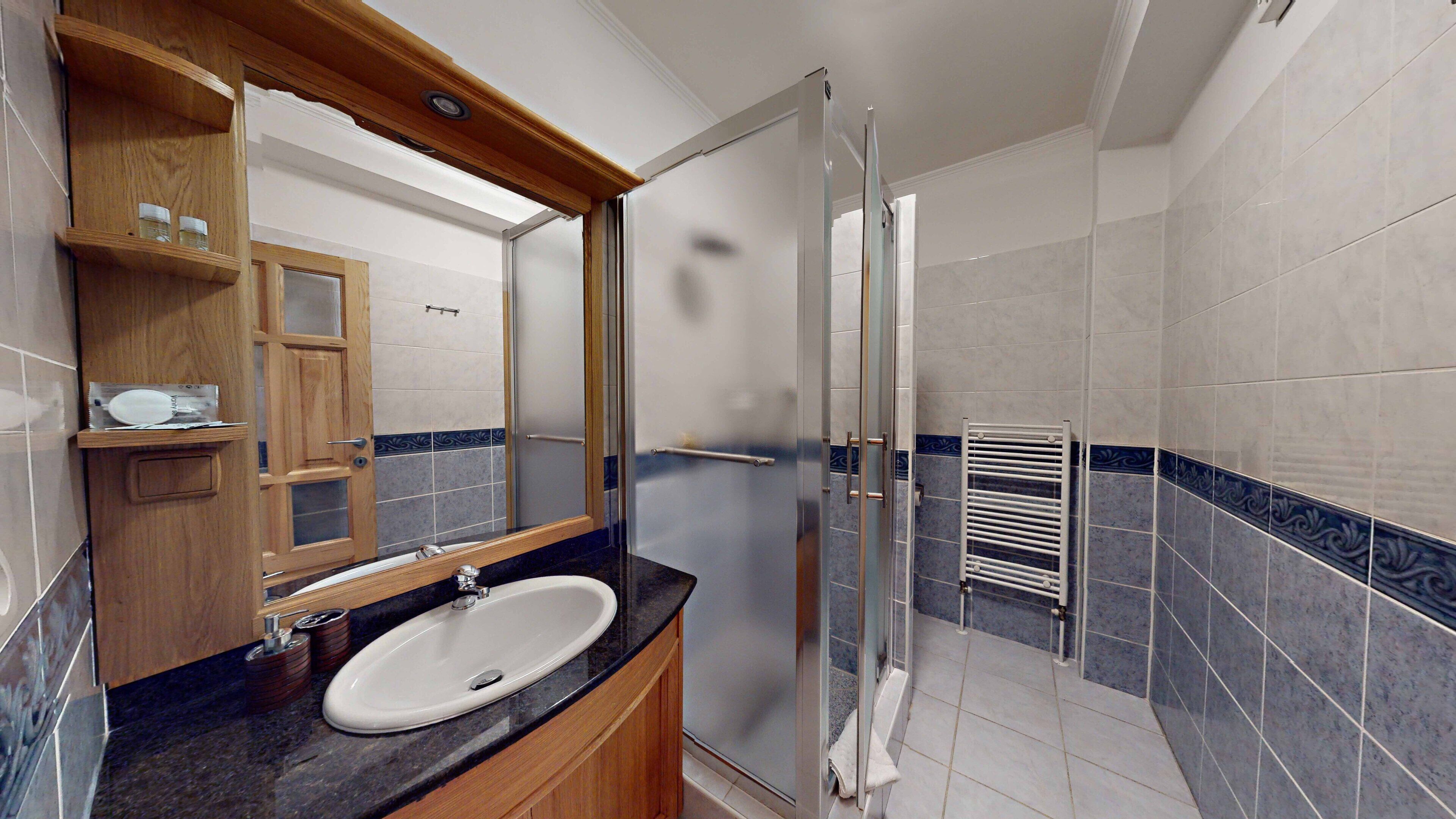 Un bagno moderno con lavandino, specchio e doccia.