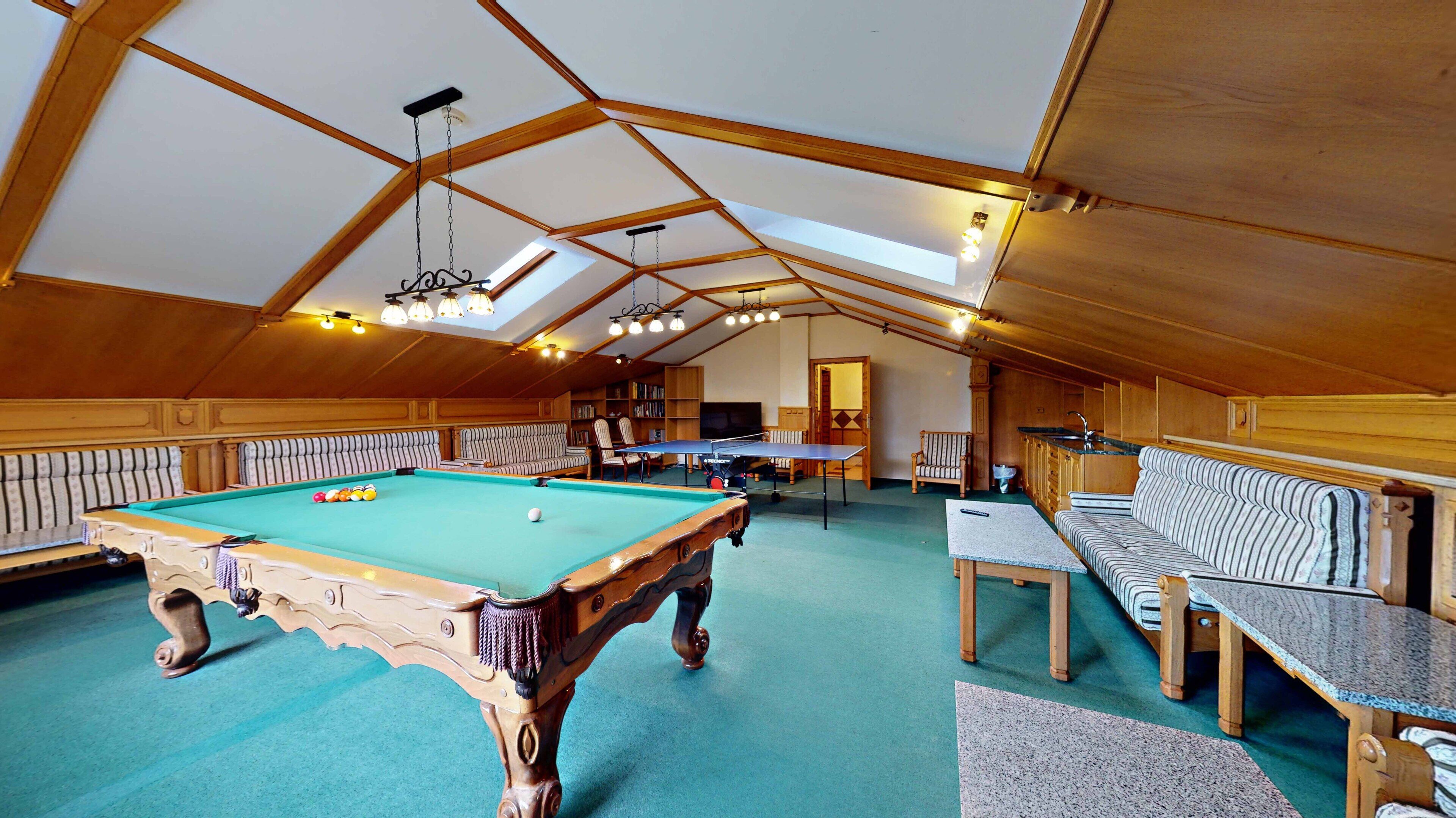 Una habitación amplia con mesa de billar, sofá y mesa de ping pong.