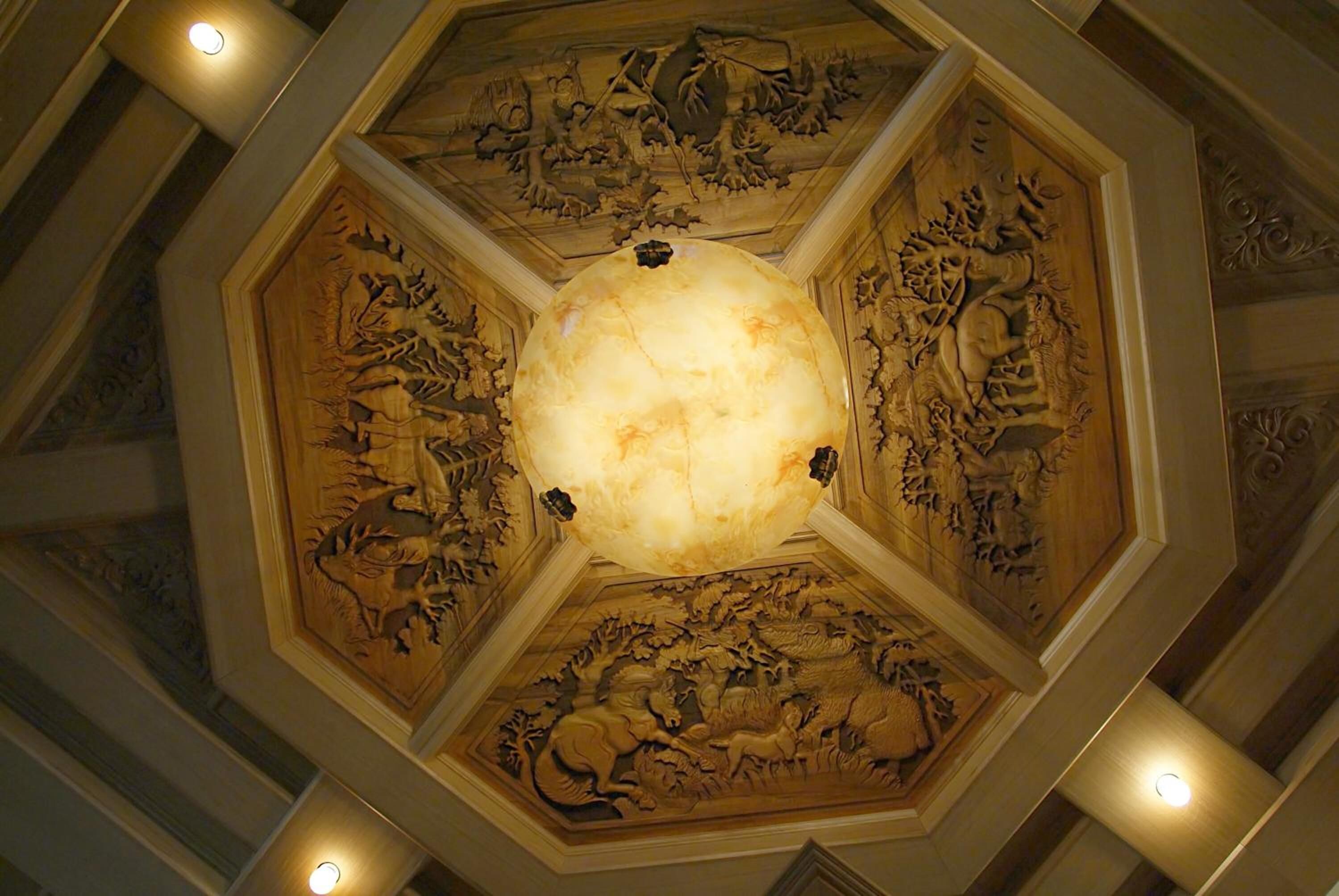 Techo con elaboradas esculturas y una lámpara central.