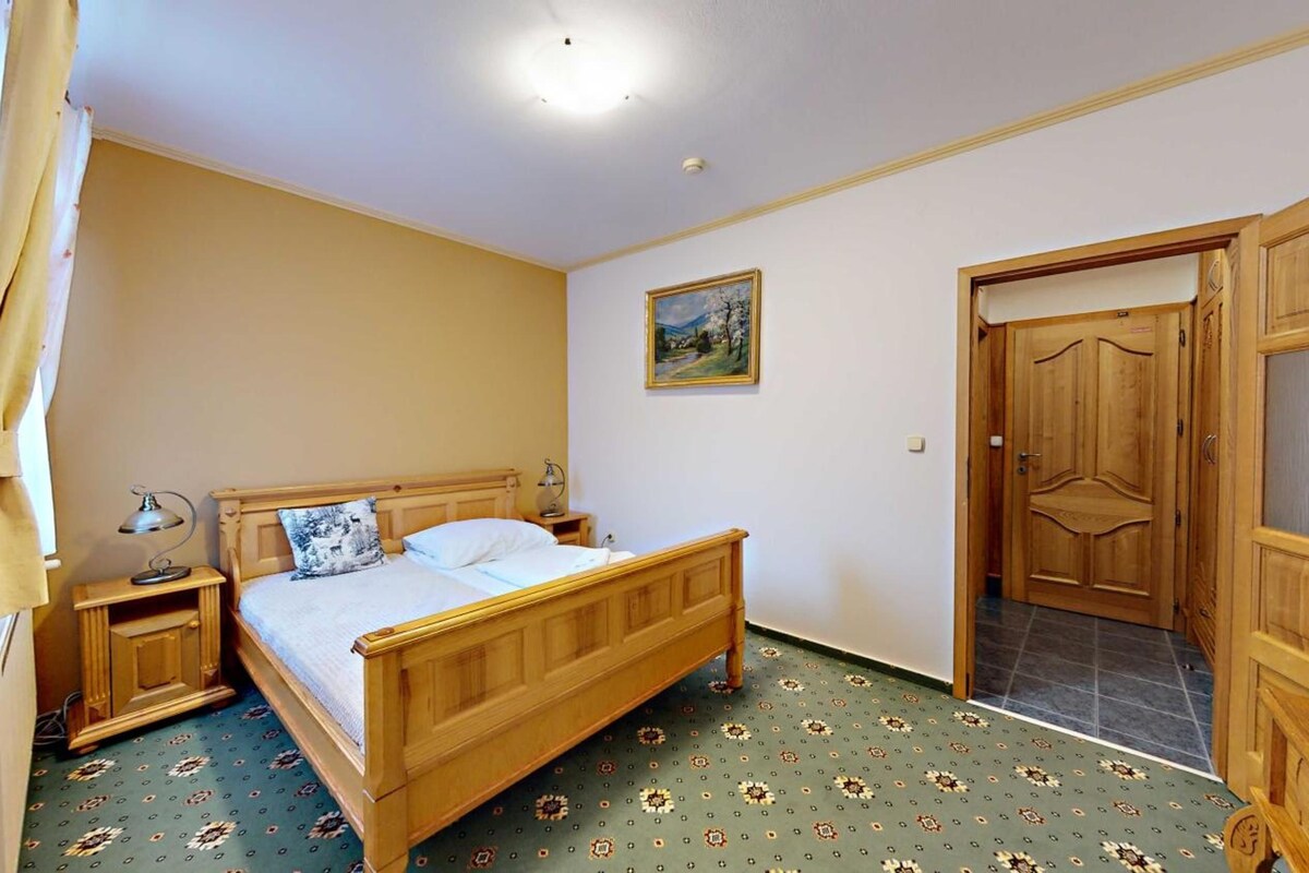 Un dormitorio con una cama de madera, mesitas de noche, un armario y un cuadro en la pared.