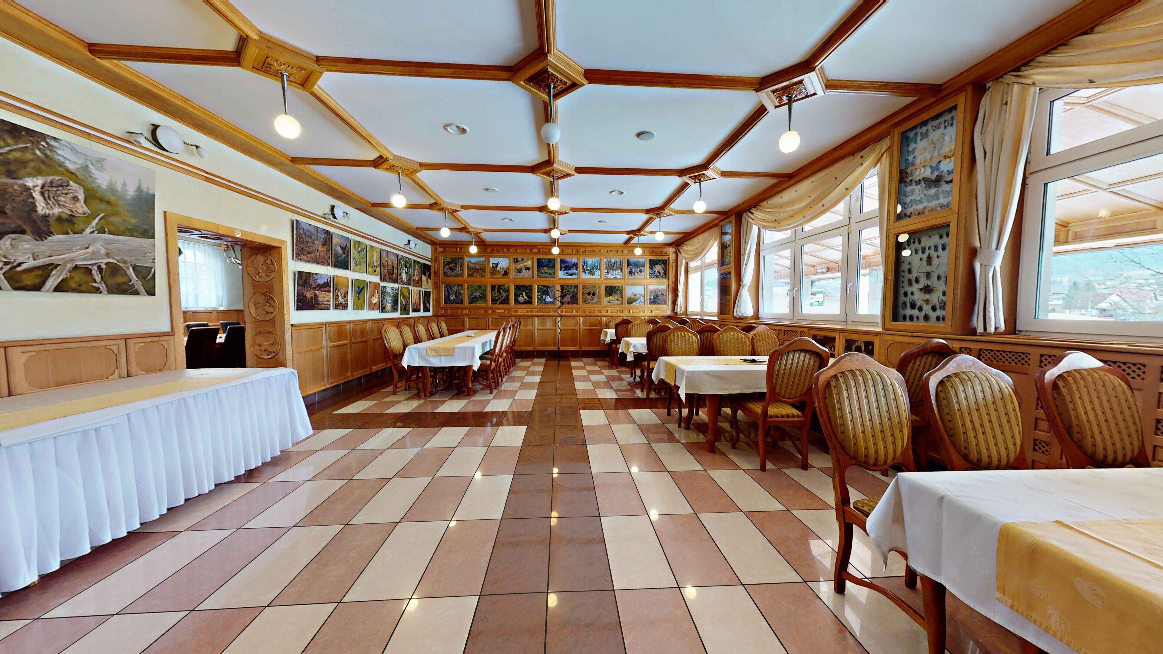A restaurant with a checkered floor, wooden ceiling beams, and framed pictures on the walls.