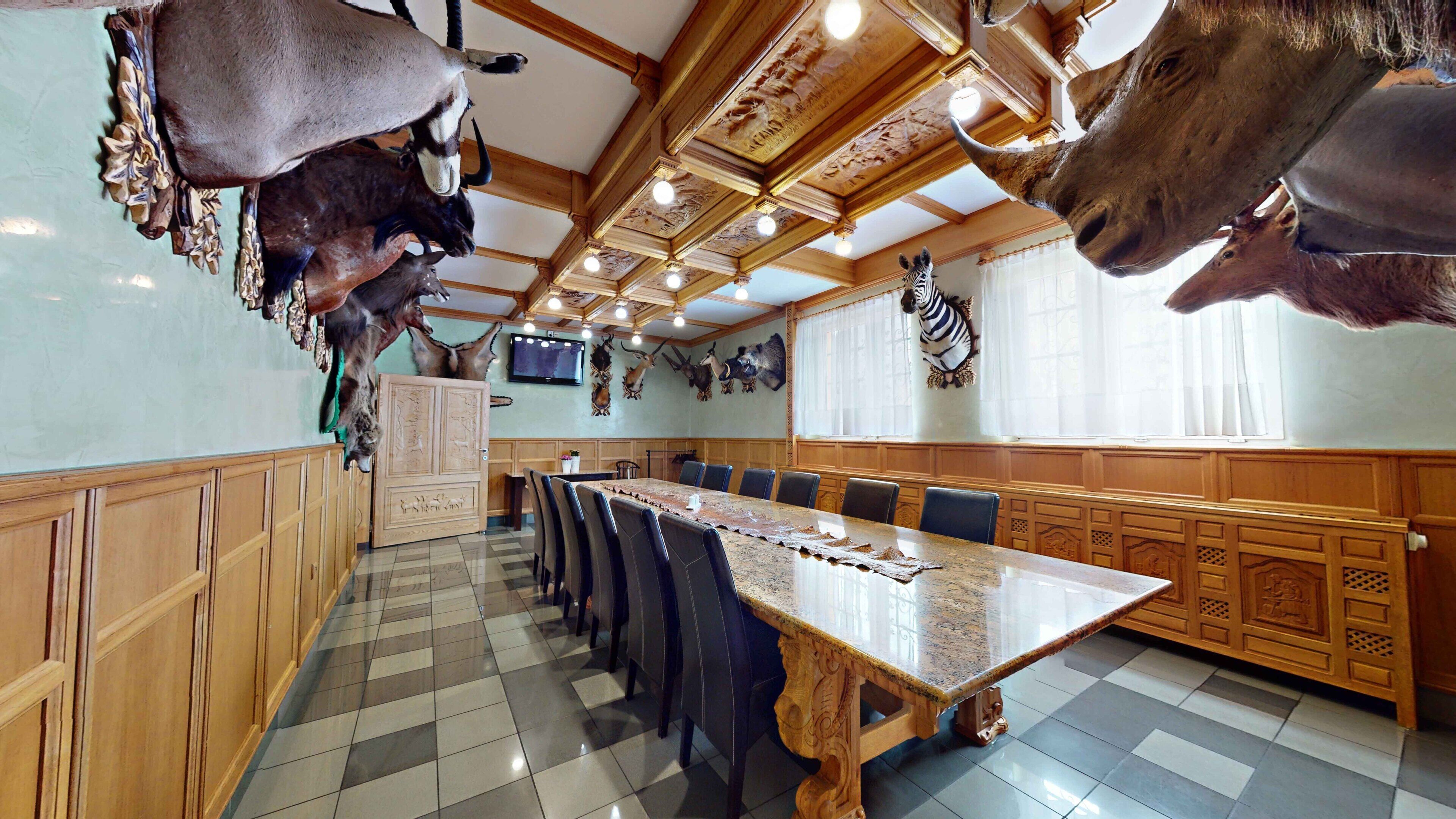 Un restaurante con una larga mesa de comedor, paneles de madera y monturas de animales en las paredes.