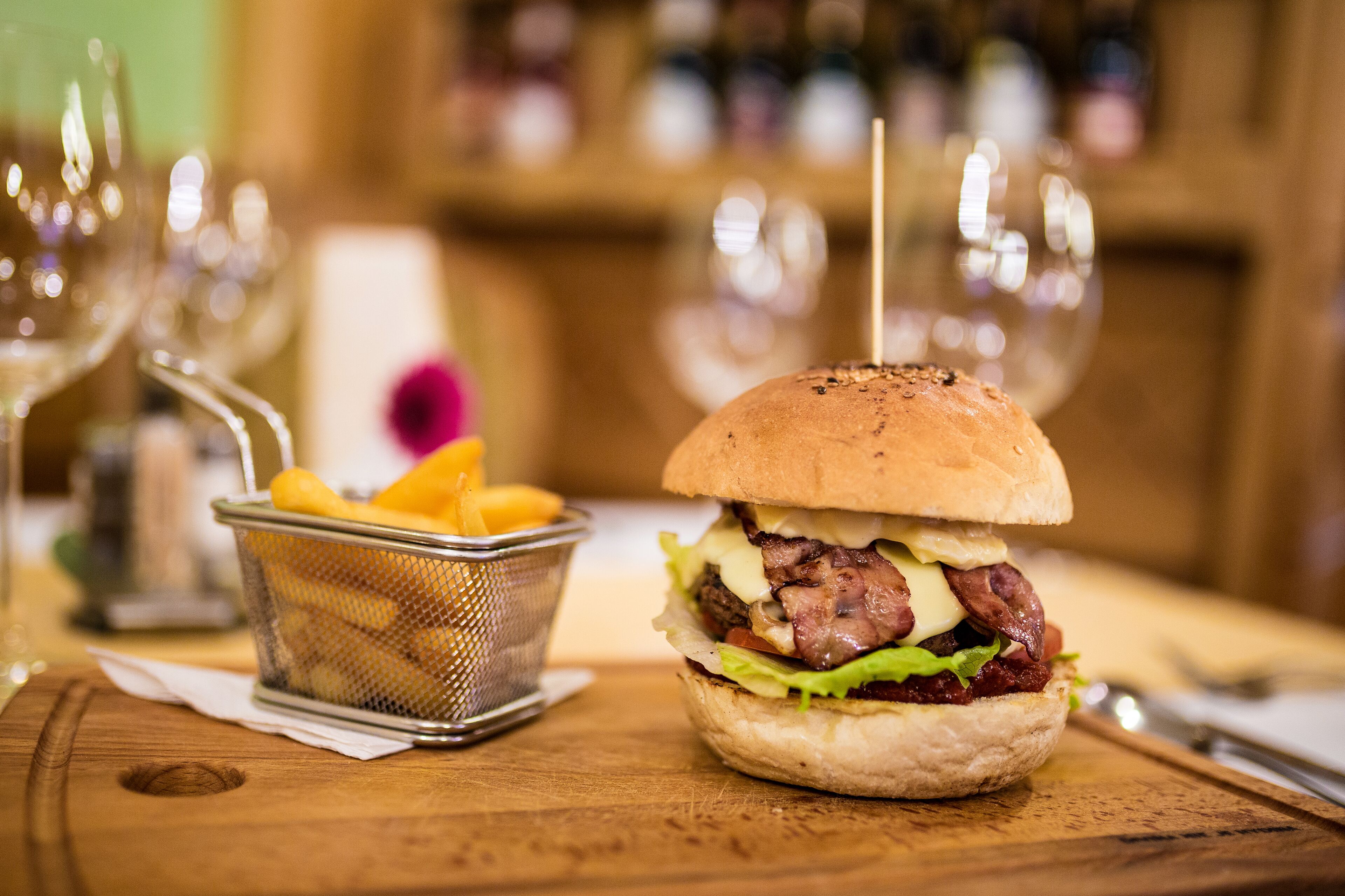 A burger with fries on a wooden table.