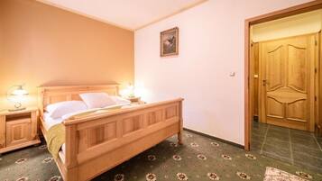 A bedroom with a wooden bed, nightstands with lamps, a door, and a patterned carpet.