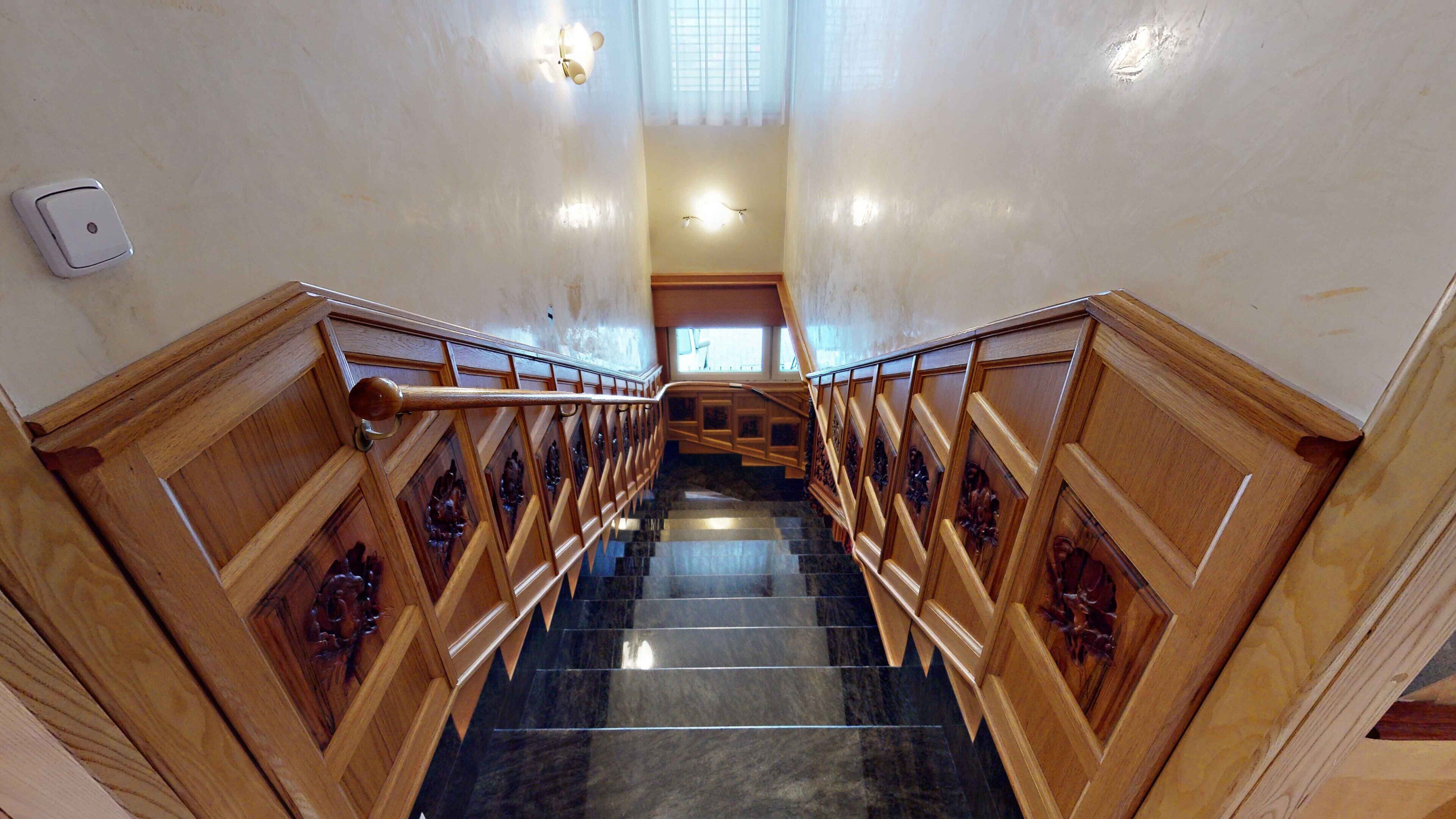 A grand staircase with wooden railings and marble steps, leading to an upper floor.