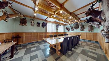 A restaurant with a long wooden table and chairs, surrounded by walls adorned with mounted animal heads.