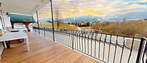 A wooden deck with a metal railing overlooking a mountainous landscape.