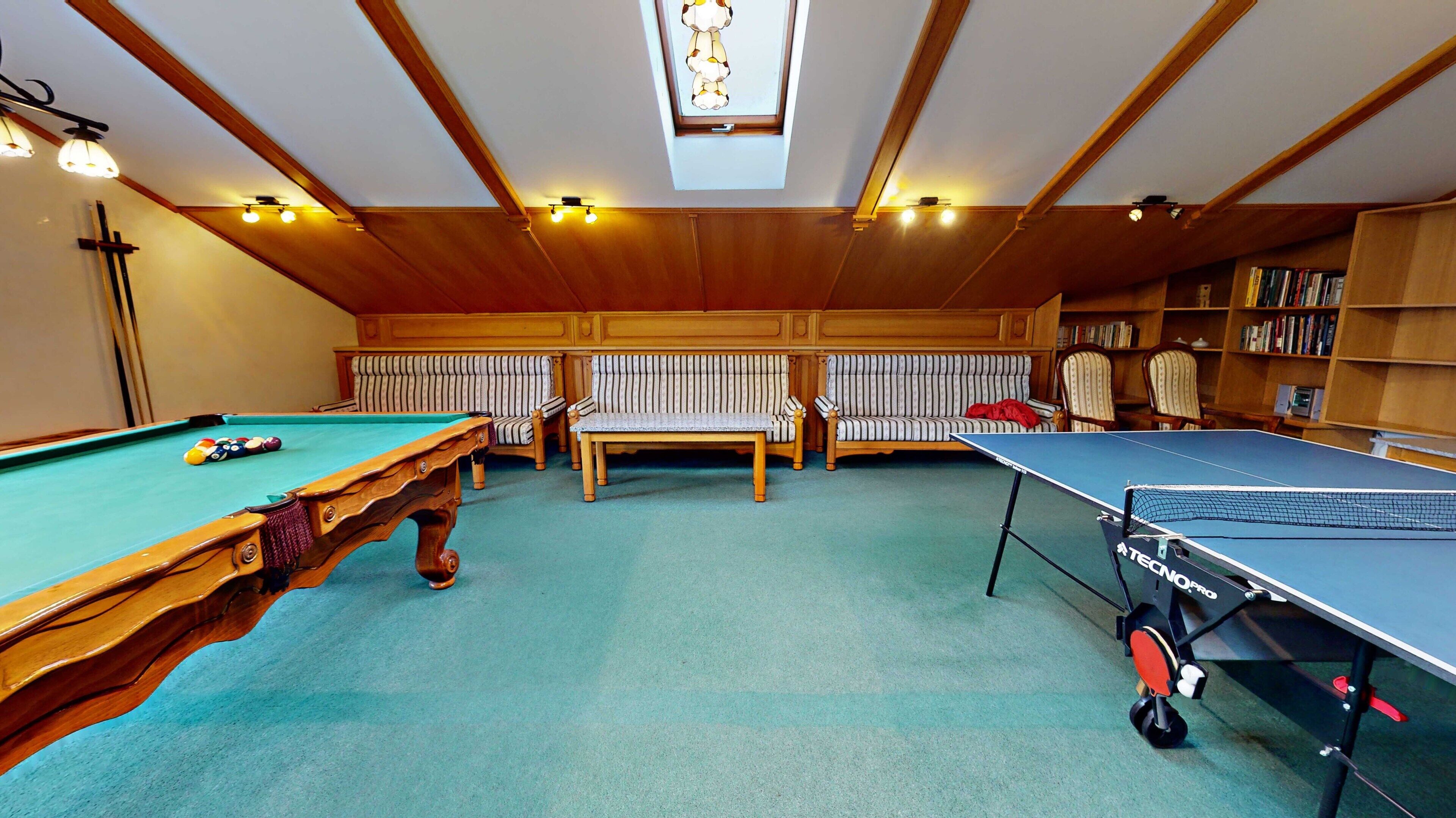 A recreational room with a pool table, a ping pong table, and a billiards table.