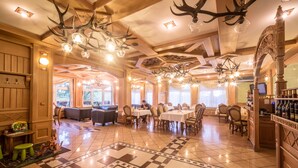 Ein Restaurant mit Schachbrettboden, Holzmöbeln und Hirschgeweih-Leuchtern.