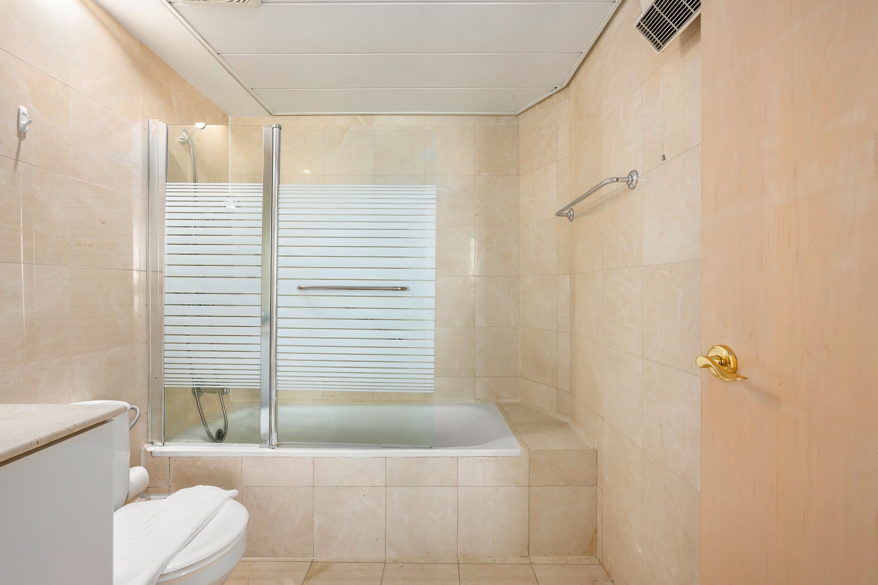 A modern bathroom with a glass-enclosed shower, a bathtub, and a toilet.