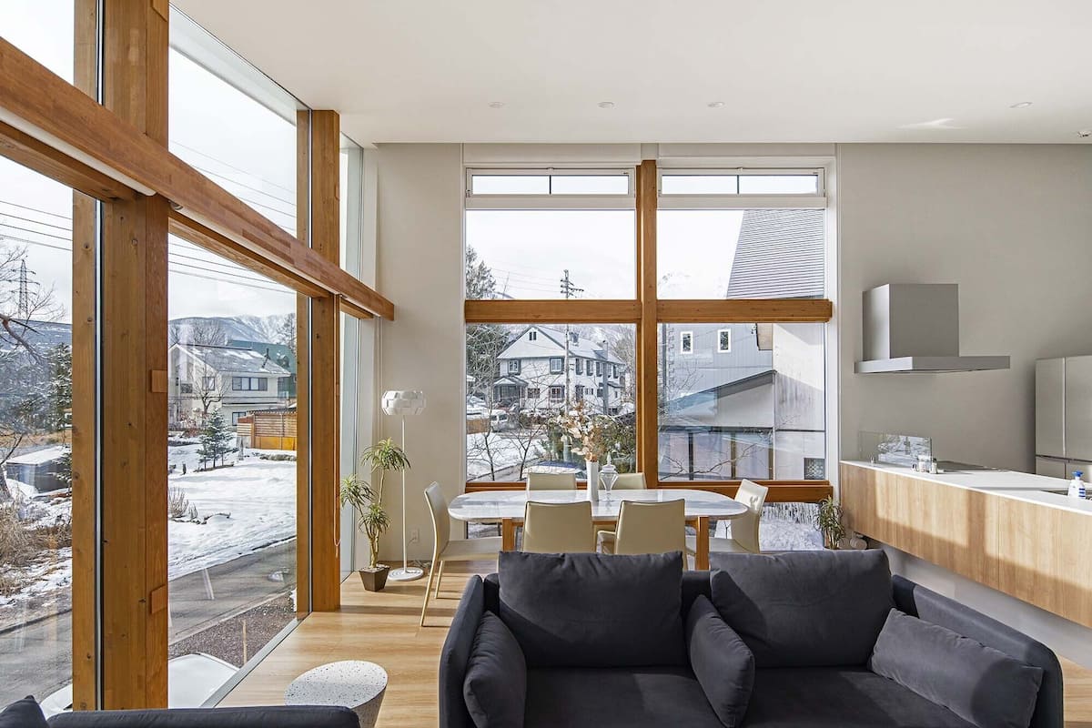 A modern interior with large windows, a dining area, and a kitchen.
