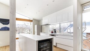 Una cocina moderna con armarios blancos, horno empotrado y un ventanal con vistas al exterior.