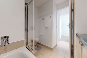 A modern bathroom with a glass shower enclosure, a toilet, and a bathtub. - Portico Beachfront Condo (Cape Town)