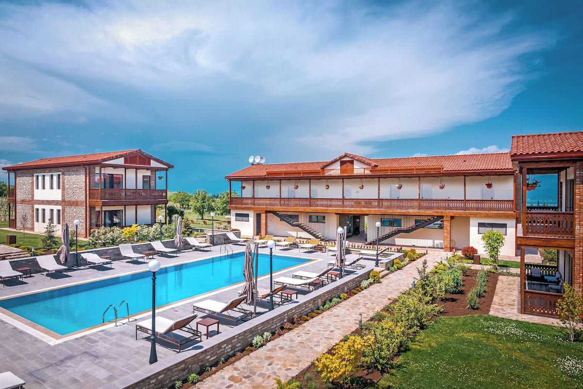 A resort with a swimming pool, lounge chairs, and a well-maintained garden.