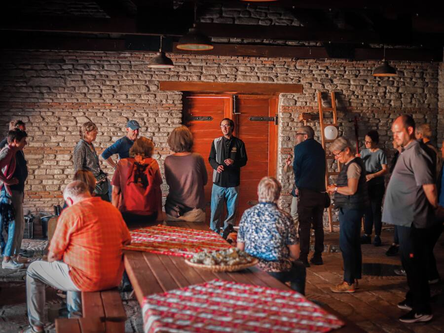 Un grup de persones en un entorn rústic, amb parets de pedra i bancs de fusta.