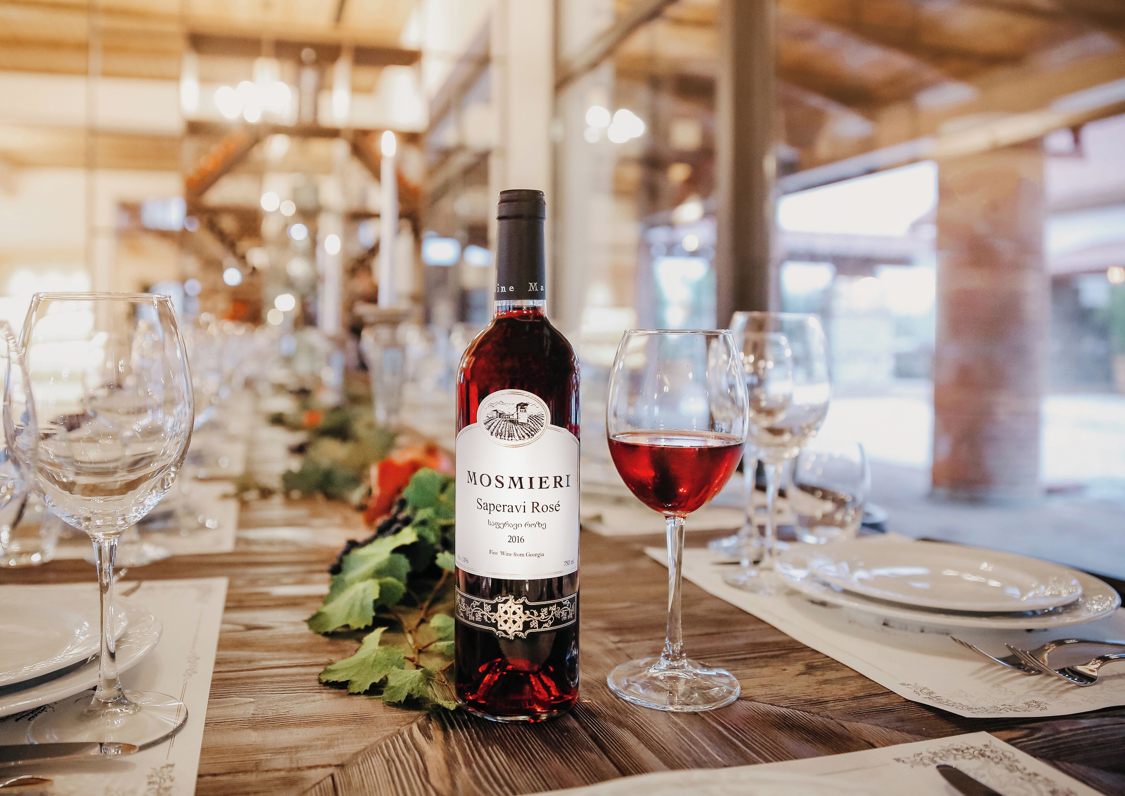 A table set for dining with a bottle of Saperavi Rosé wine, glasses, and plates.