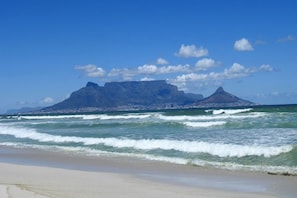 A beach with waves and a mountain in the background.