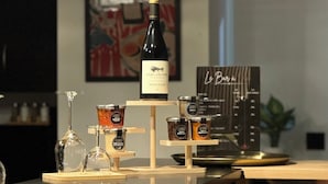 A bar area with a wine bottle, glasses, and condiments on a wooden counter. - Le H85 (Chatte)