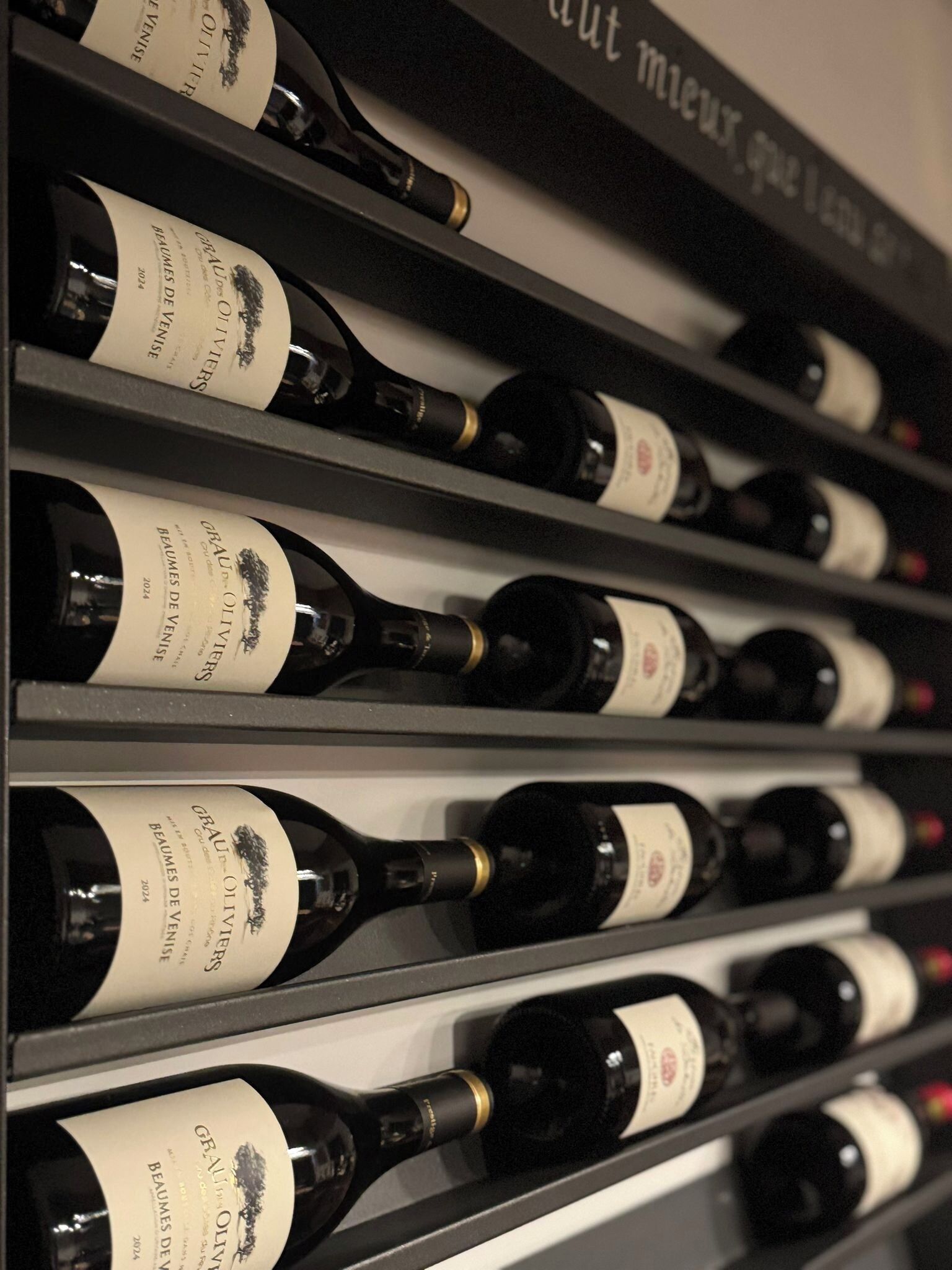 A wine rack with multiple bottles of 'GRATU OLI' wine.