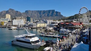 A marina with boats docked, a Ferris wheel, and buildings in the background. - Eden on the Bay Apartment 67B (Cape Town)
