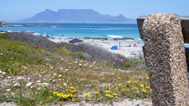 A beach with tents, a clear sky, and distant mountains. - Eden on the Bay Apartment 67B (Cape Town)