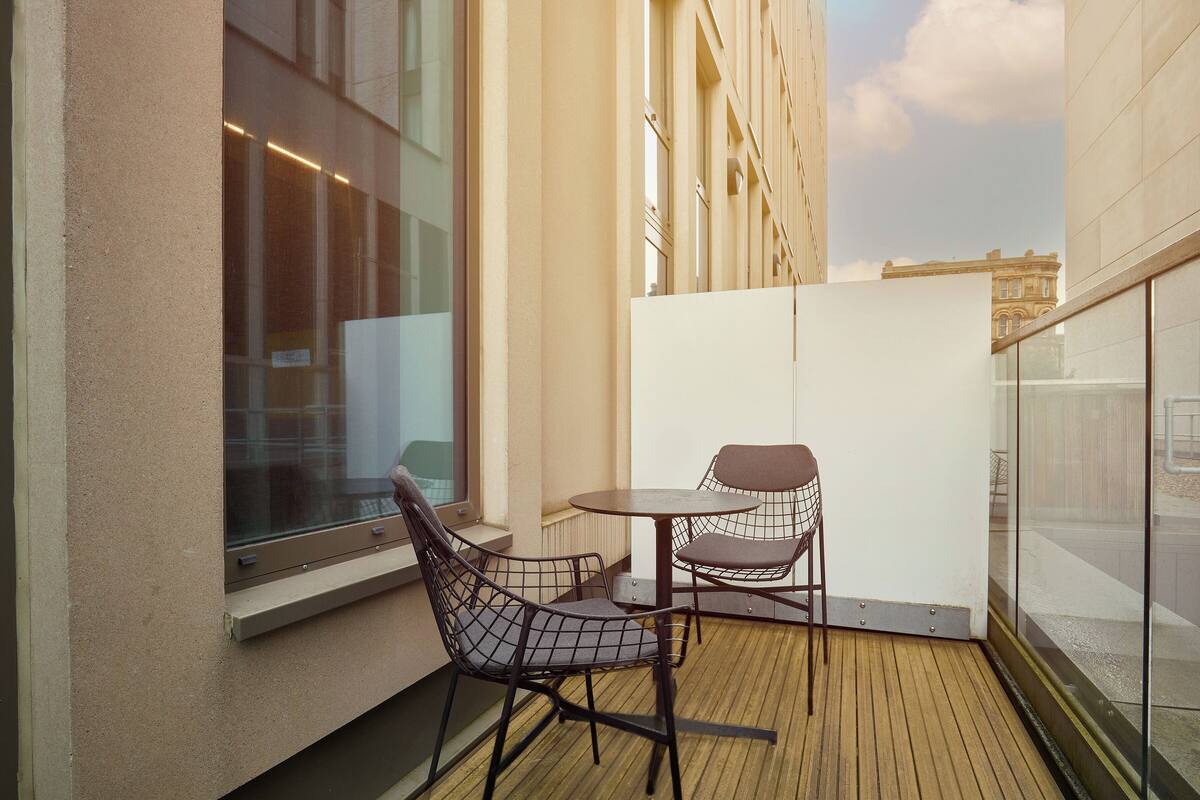 A balcony with a wooden floor, two chairs, and a small table.