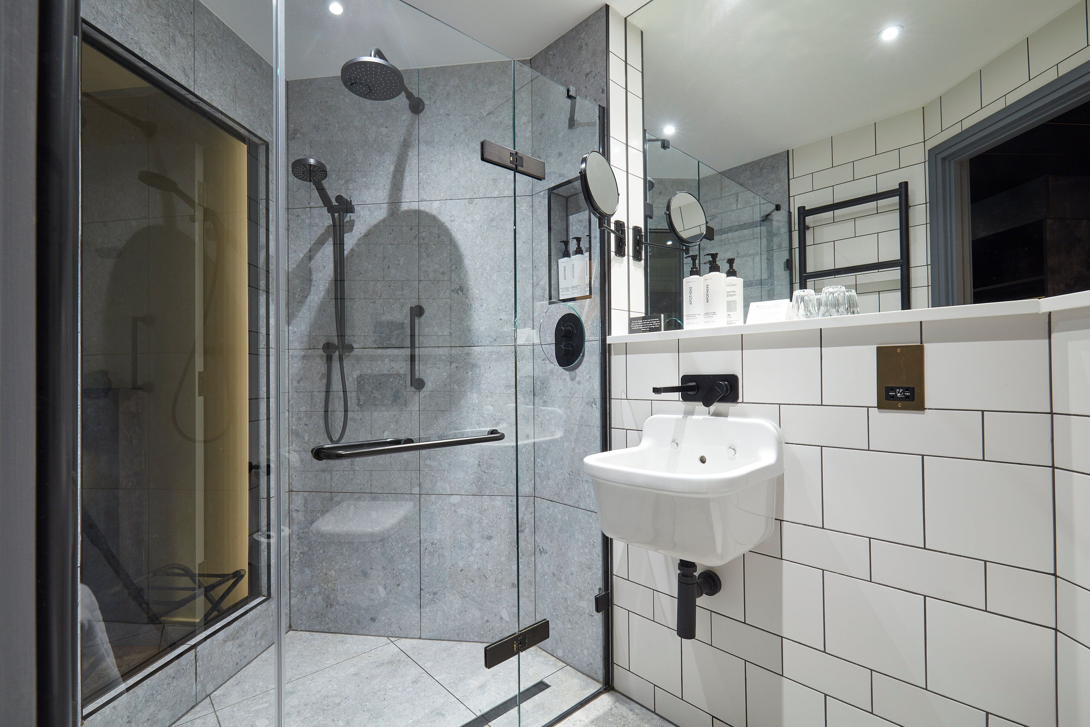 A modern bathroom with a glass-enclosed shower, a white sink, and a large mirror.