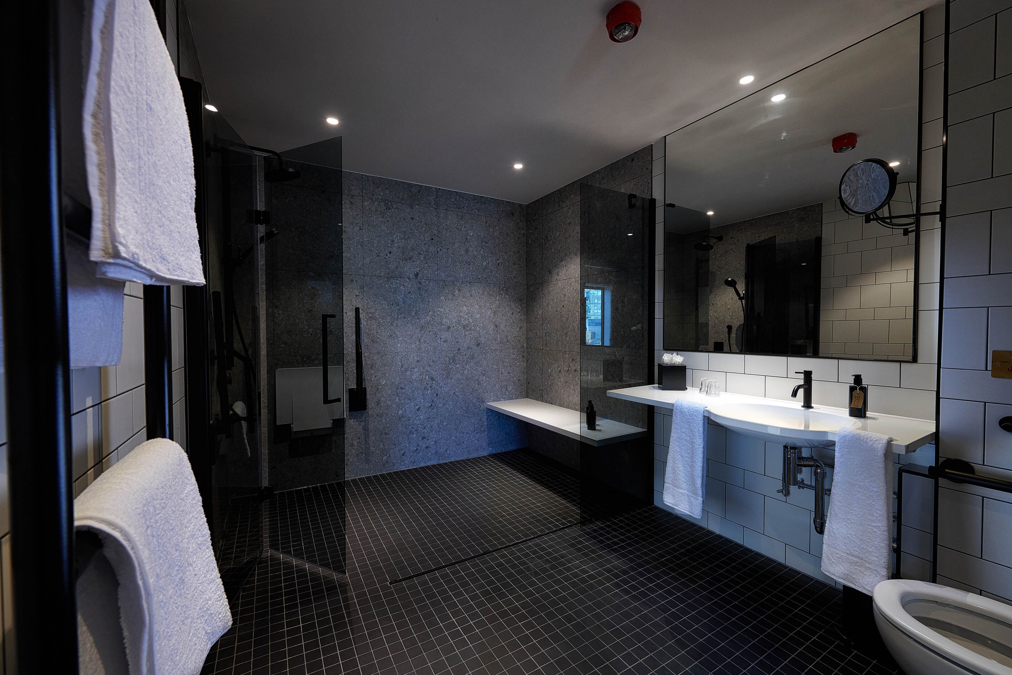 Un baño moderno con cabina de ducha de vidrio, lavamanos dobles y un espejo grande.