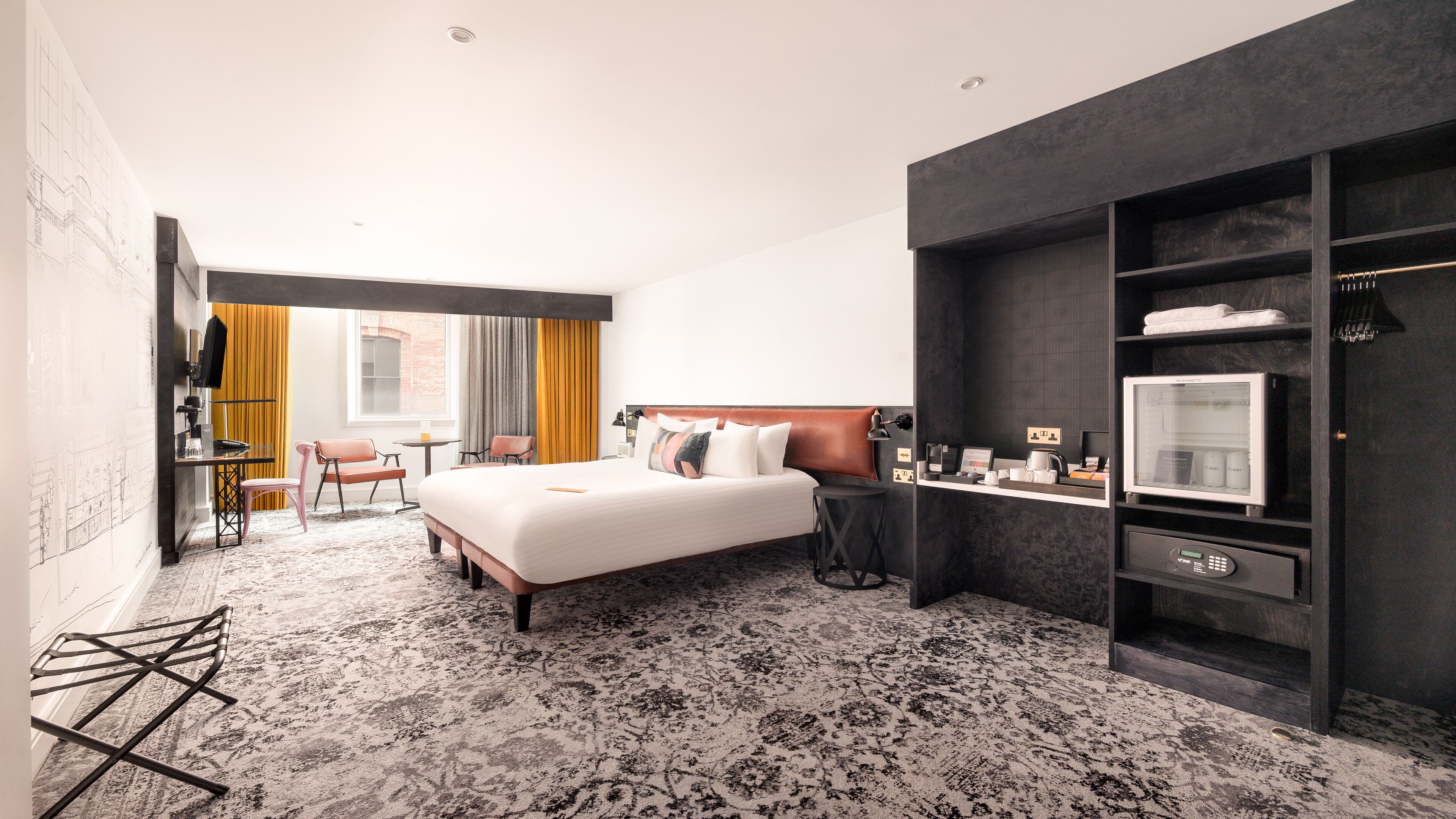 Ein Hotelzimmer mit einem großen Bett, einem Schreibtisch, einem Sessel, einem kleinen Tisch und einem Kleiderschrank.