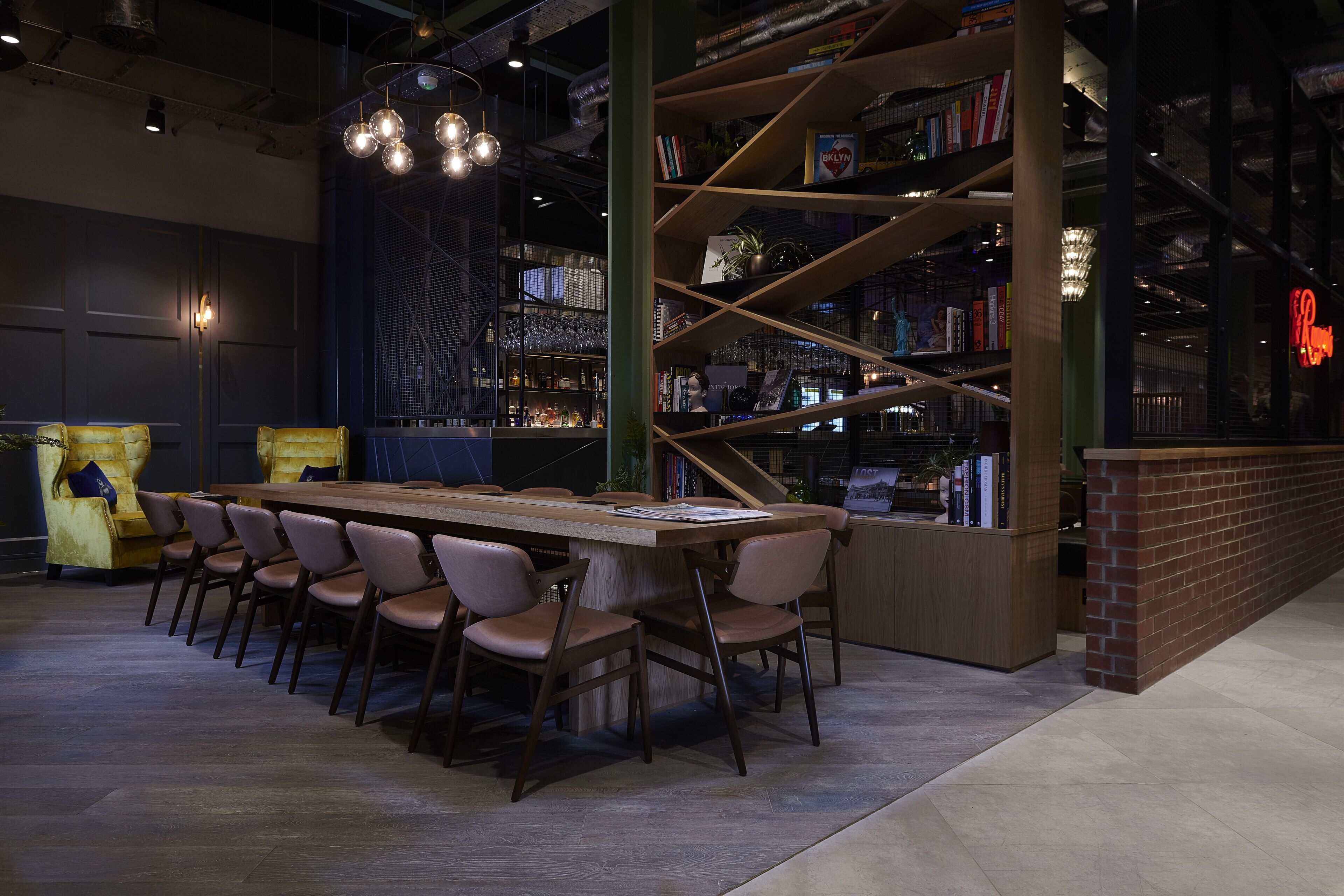 Een moderne bibliotheek met een houten tafel en stoelen, omringd door boekenplanken.