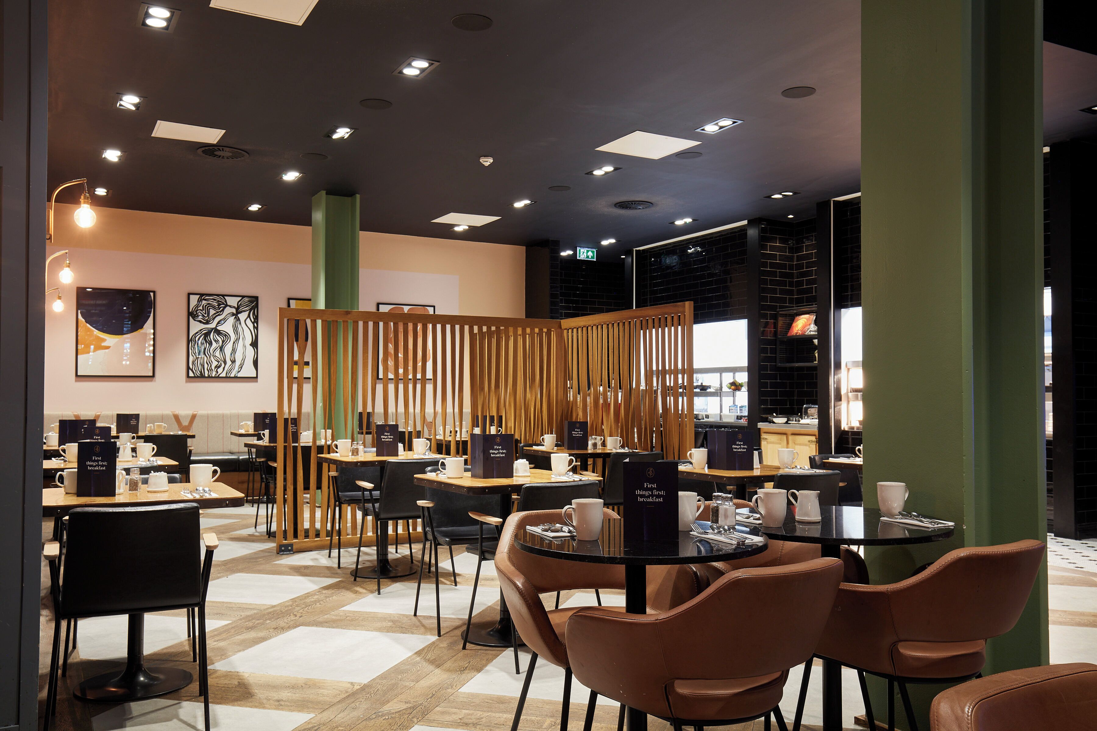 A modern cafe with multiple seating areas, including round tables and booths, and a visible menu board.