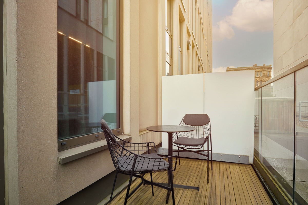 A balcony with a wooden floor, two chairs, and a small table.
