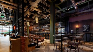 A modern bar area with exposed ductwork, wooden bar counters, and multiple seating options including bar stools and tables. - voco Manchester City Centre by IHG (Manchester)