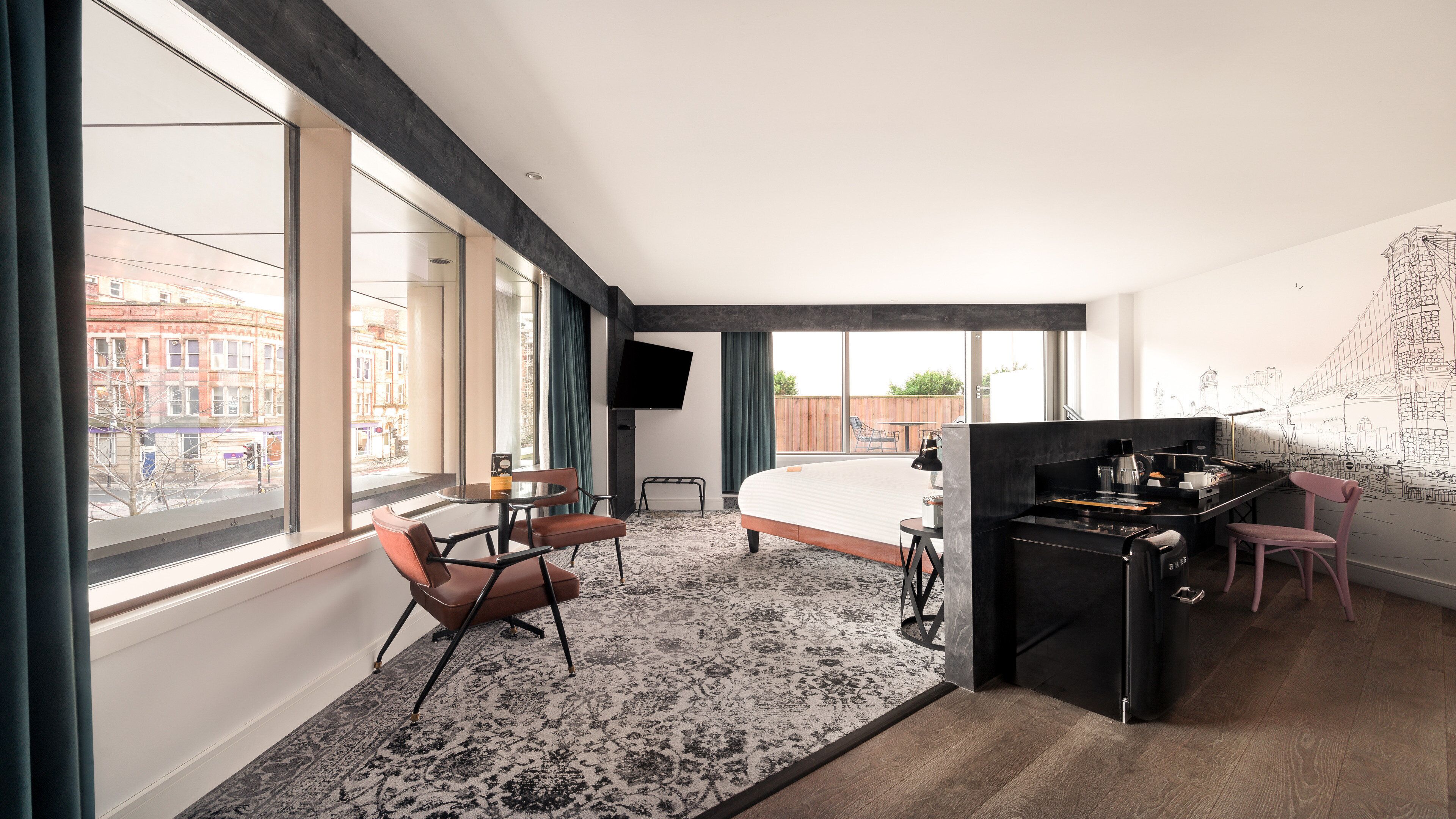 Een moderne hotelkamer met een groot bed, een bureau, een stoel, een bijzettafeltje en een televisie.