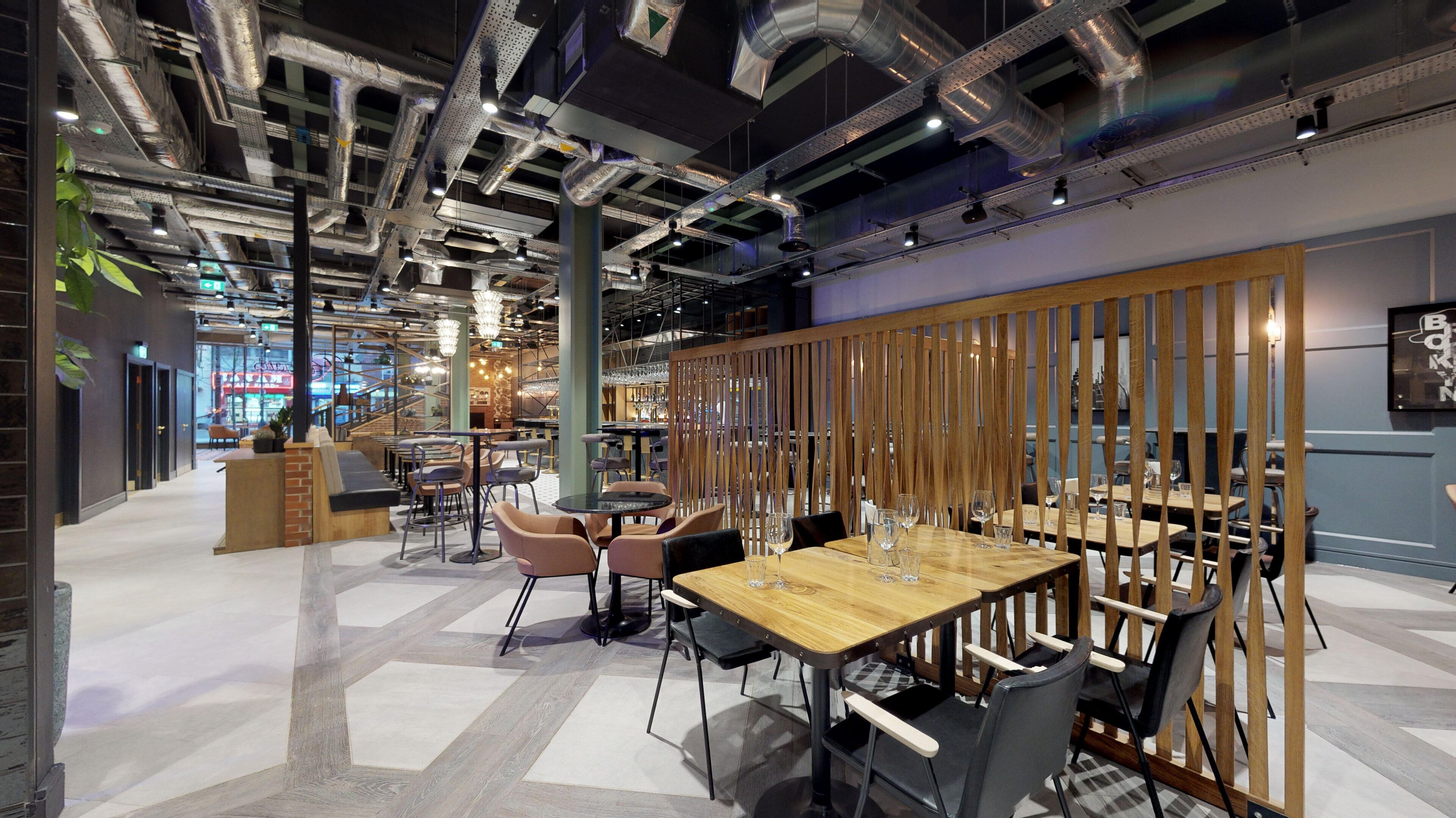 A modern restaurant with a mix of seating options, including tables and booths, and a decorative wooden partition.