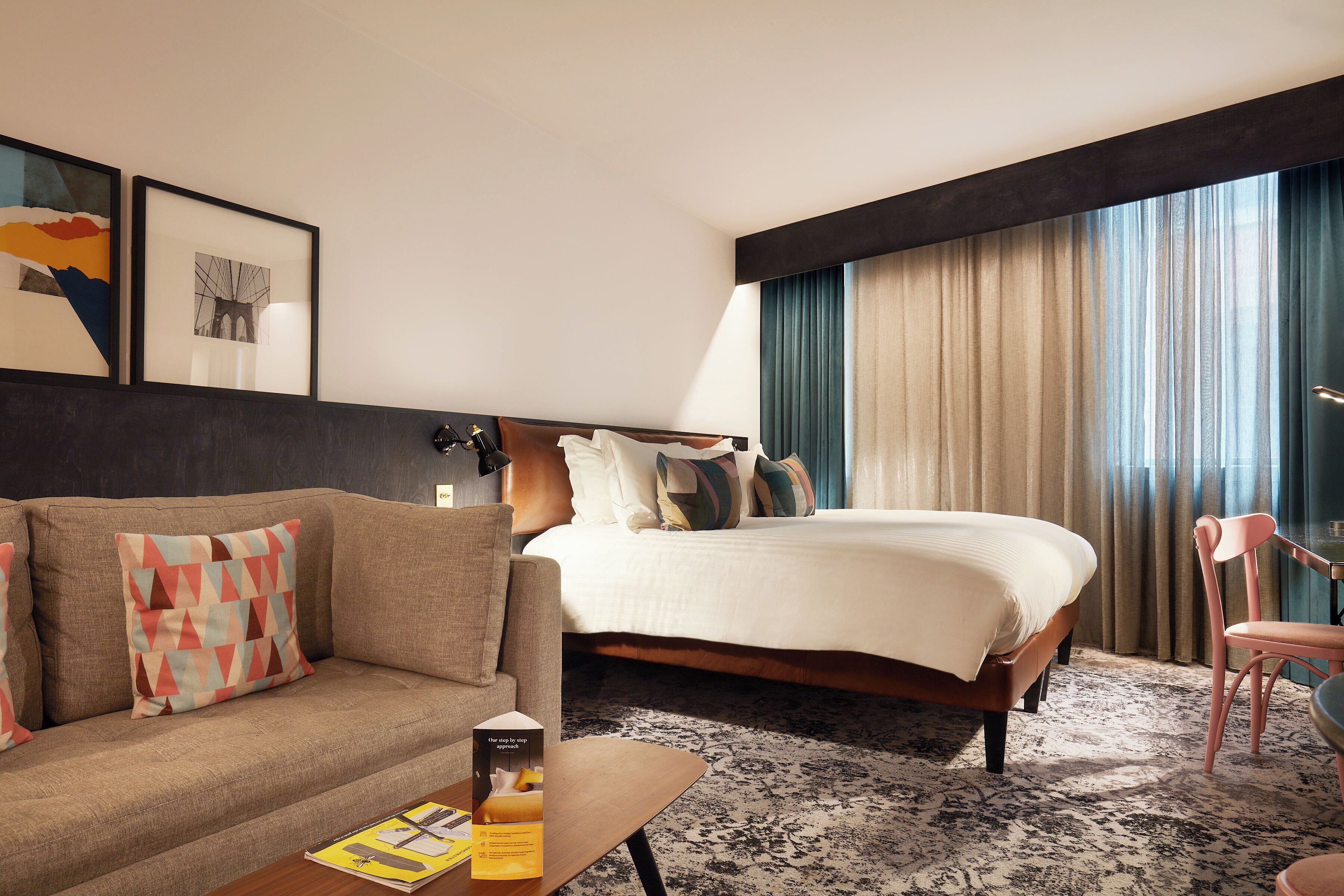 A hotel room with a bed, a sofa, a coffee table, and a chair.