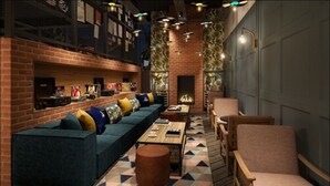 A cozy lounge area with a long blue sofa, wooden coffee table, and a fireplace. - voco Manchester City Centre by IHG (Manchester)