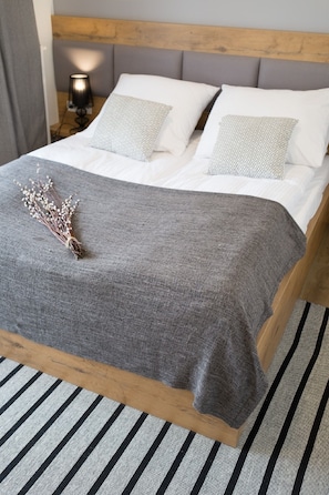 A bed with a grey blanket, white pillows, and a wooden headboard.