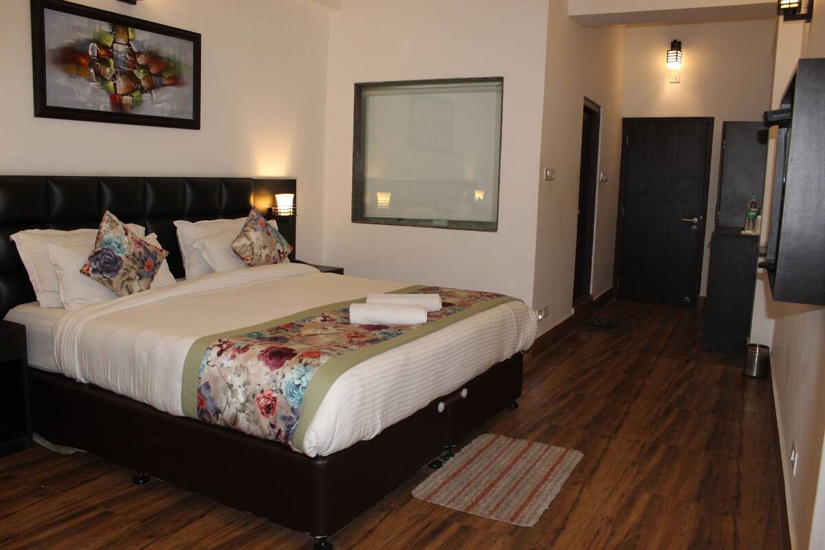 A bedroom with a large bed, a headboard, a window, and a door.