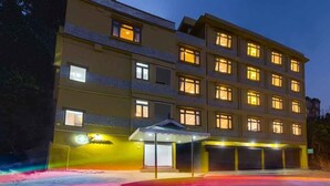 Un hôtel à plusieurs étages, doté de fenêtres illuminées et d’un parking couvert.